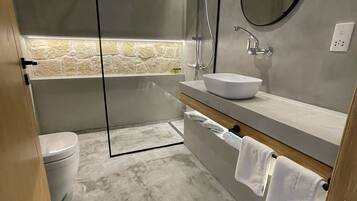 Een moderne badkamer met een douchecabine van glas, een vrijstaand bad, een witte wastafel en een grote spiegel.