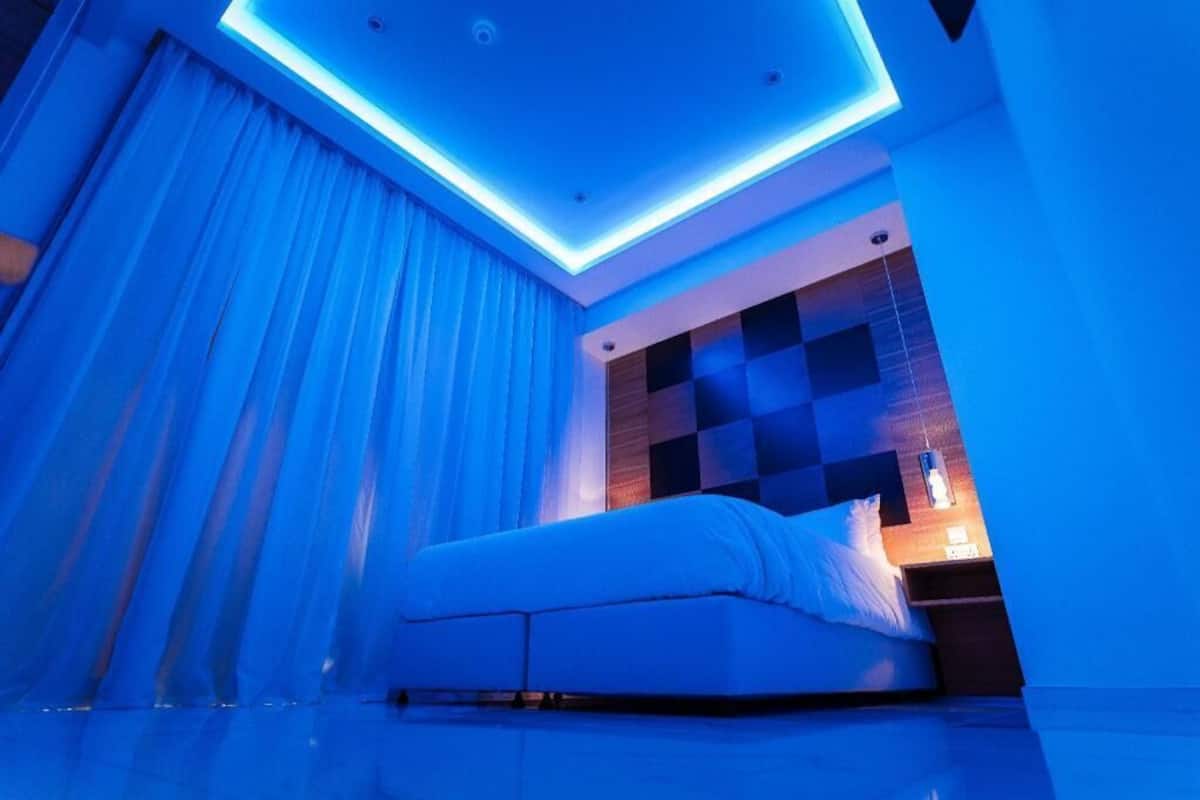A modern bedroom with a bed, a nightstand, and a wall with a geometric pattern.