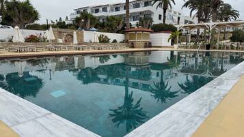 Una piscina al aire libre de temporada, sombrillas