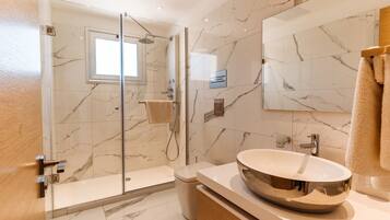 A modern bathroom with a glass-enclosed shower, a large mirror, and a round vessel sink.