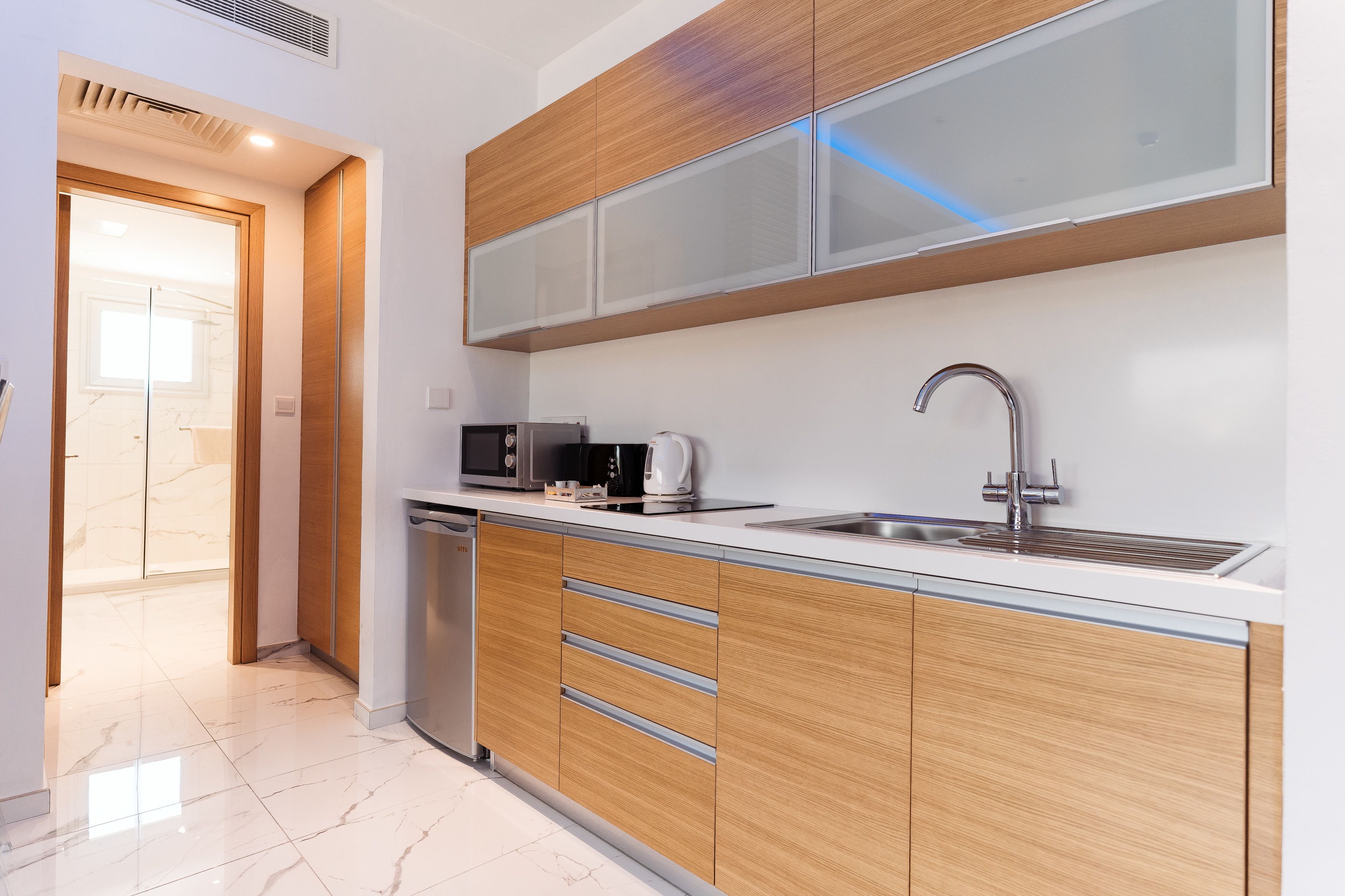 A modern kitchen with wooden cabinets, a stainless steel sink, and a microwave.