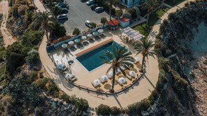 Luchtbeeld van een resort met een zwembad, ligbedden en palmbomen.