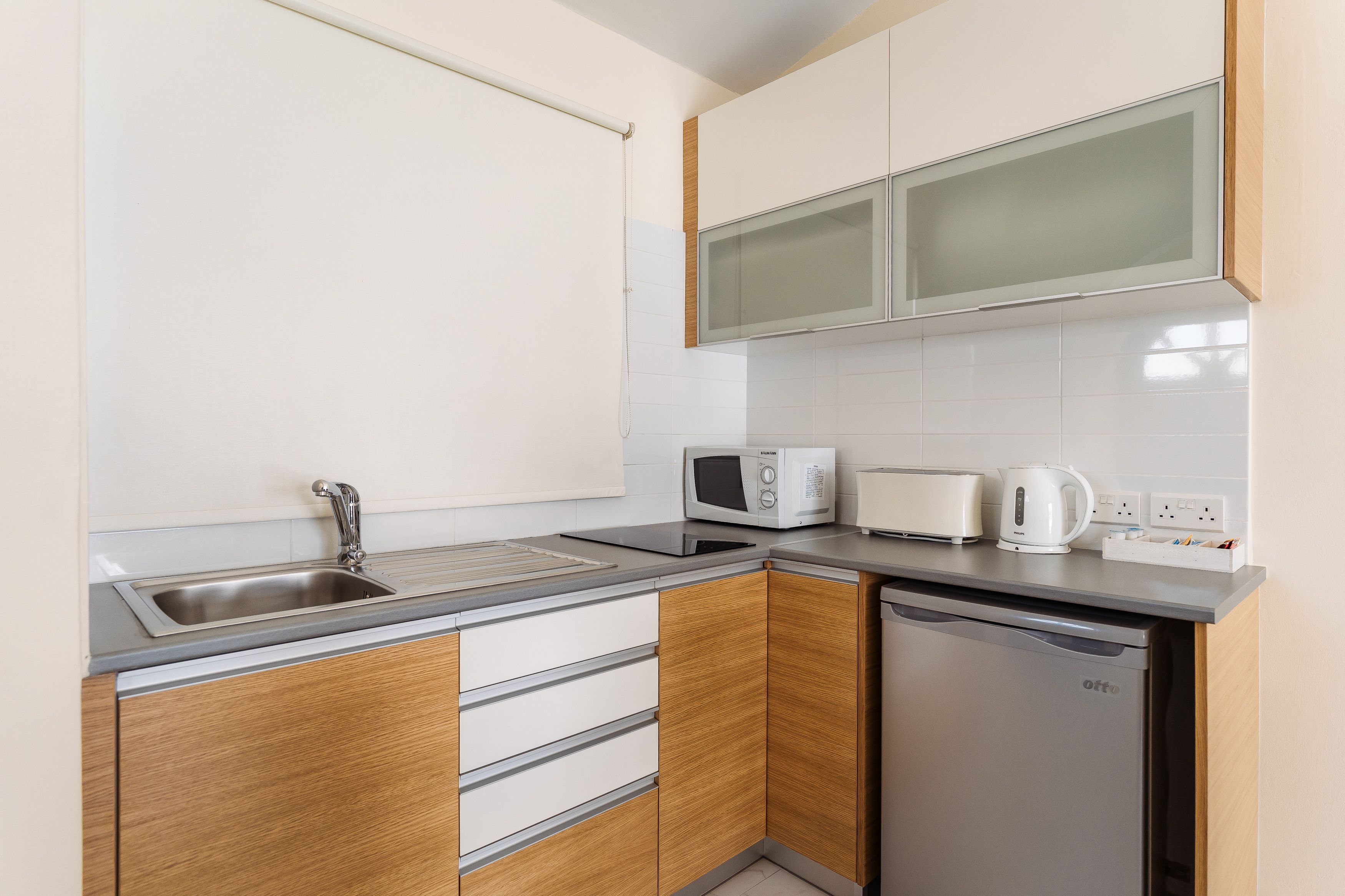 A compact kitchen with a sink, microwave, toaster, and a dishwasher.