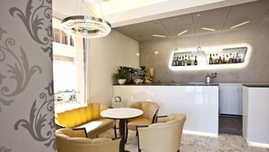 A modern bar area with a marble floor, a round table, and yellow leather seating. - Aurora (Rimini)