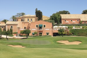 A golf course with a clubhouse and residential buildings in the background.