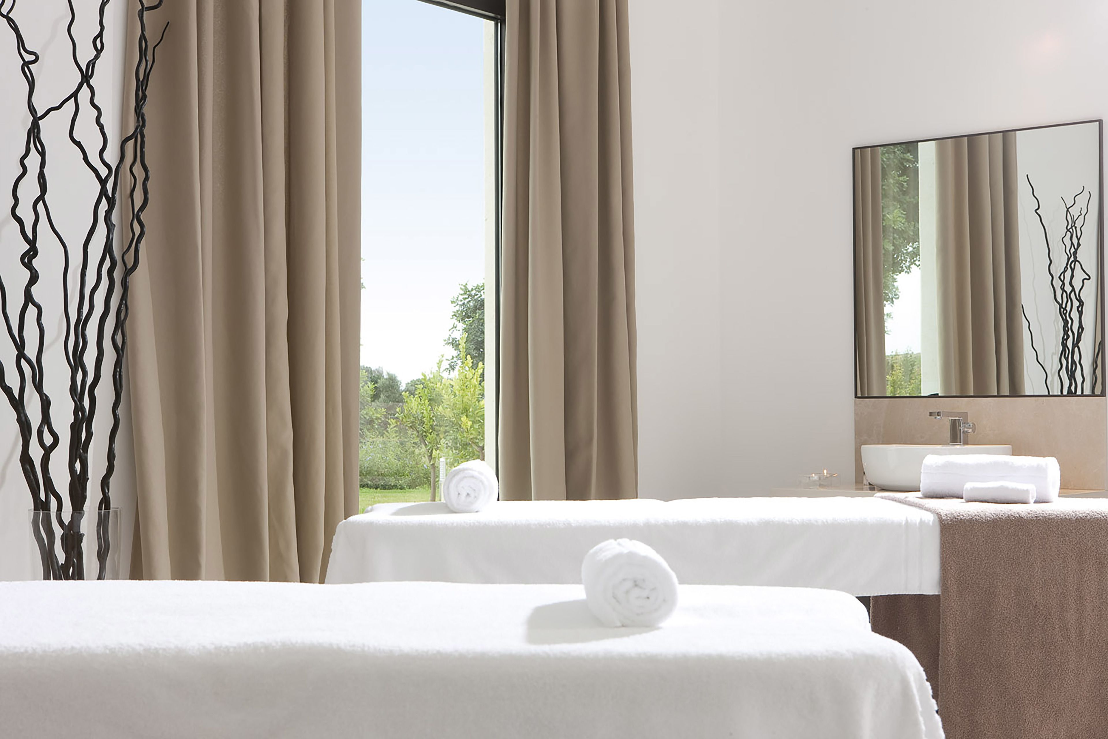 Camera d'albergo con due letti, un'ampia finestra, un bagno con lavandino e uno specchio che riflette il paesaggio esterno.