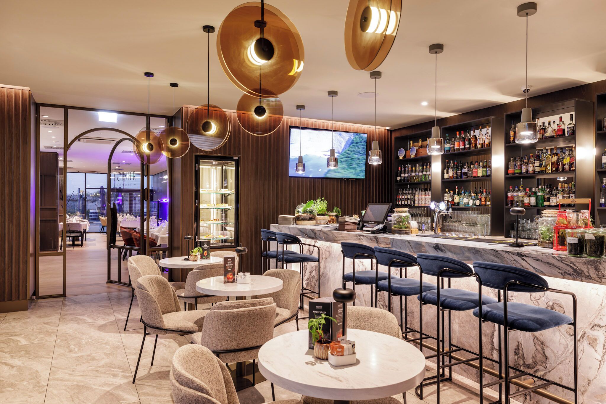 Eine moderne Bar mit Marmorplatten, Barhocker und einem Fernseher.