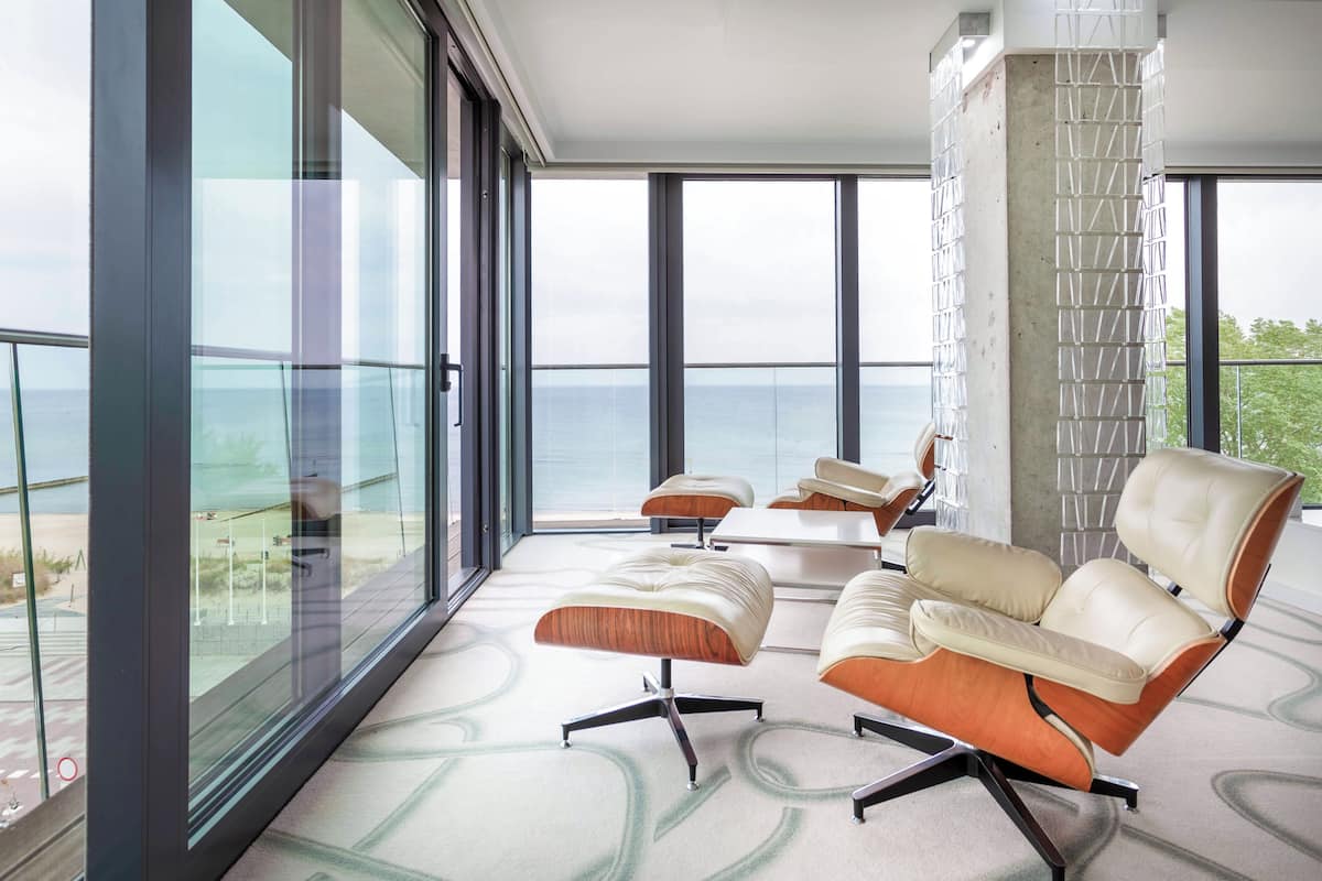 A modern room with large windows, a balcony, and contemporary furniture.