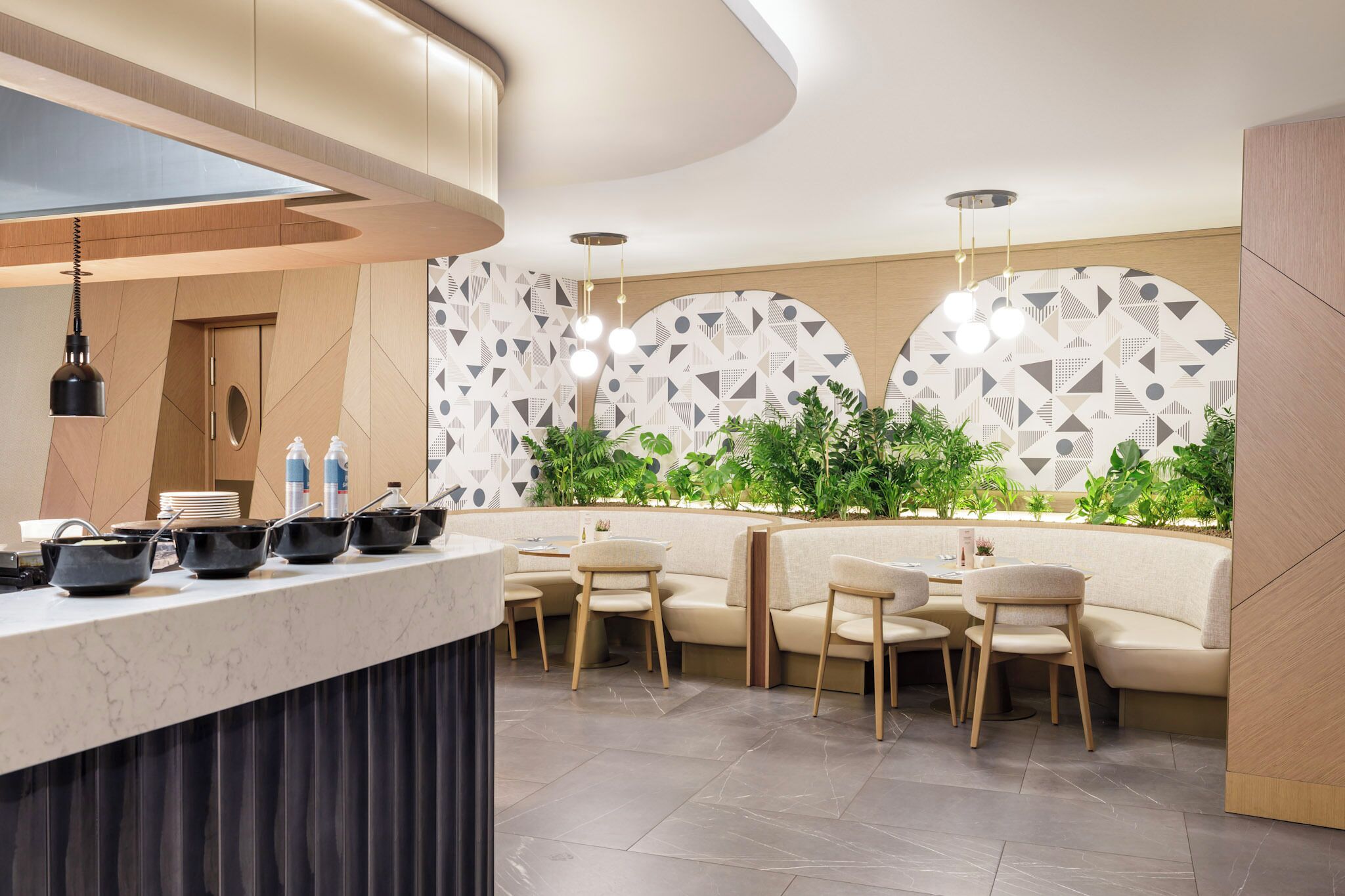 A modern restaurant with a marble counter, seating area, and geometric patterned wall.