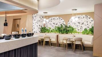 A modern restaurant with a marble counter, seating area, and geometric patterned wall.