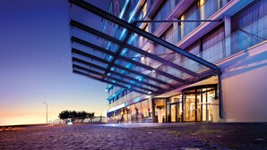 Un hotel moderno con fachada de vidrio, zona de estar al aire libre y entrada cubierta.