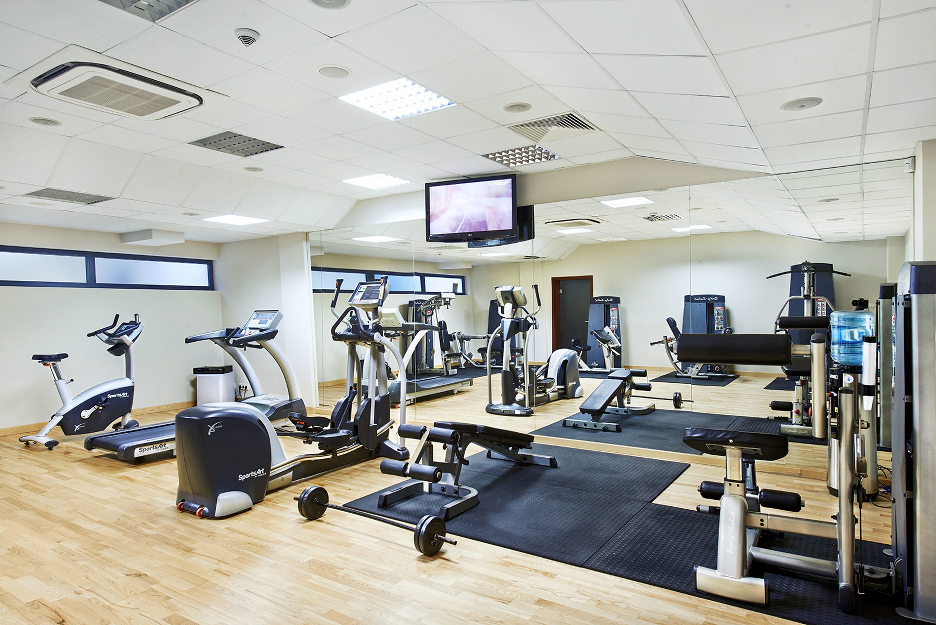 A gym with various exercise equipment, a television, and a large window.