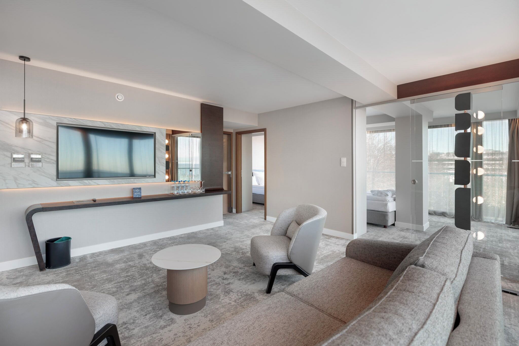 Un vestíbulo de hotel moderno con un televisor grande, zona de estar y vistas a la ciudad.