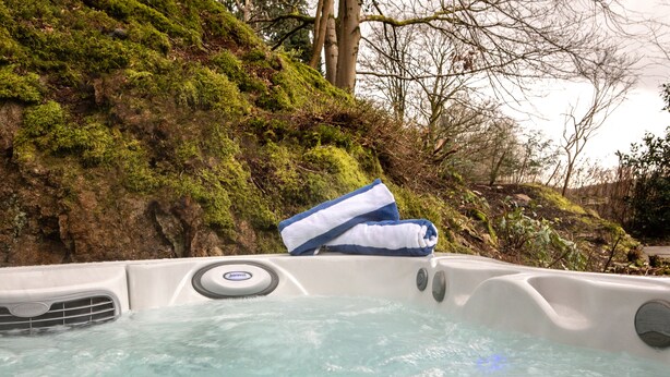 A hot tub with a blue towel on it, surrounded by greenery and trees. - Rothay Manor Hotel (Ambleside)