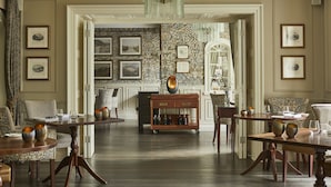 A spacious room with a large dining table, multiple chairs, and a decorative cart. - Rothay Manor Hotel (Ambleside)