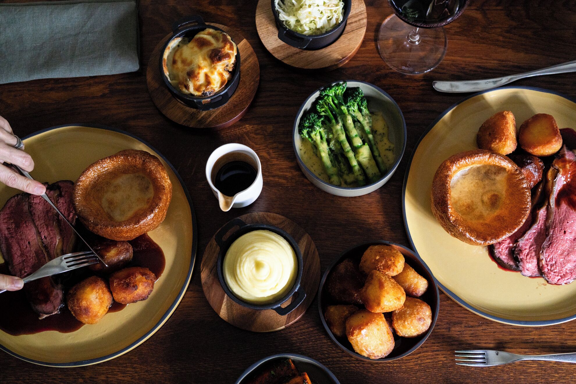 A dining table with various dishes including Yorkshire pudding, steak, and vegetables.