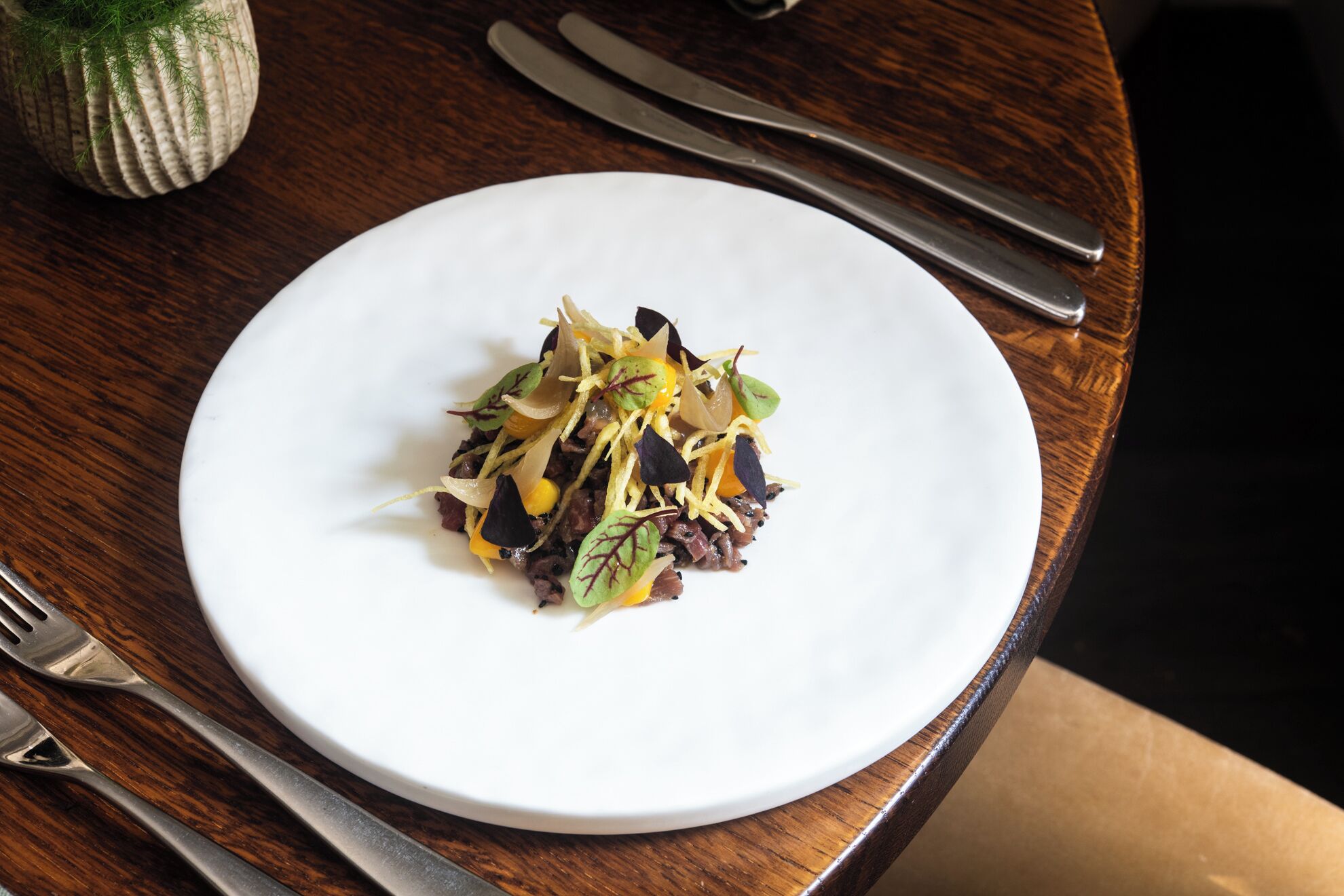 A white plate with a salad on a wooden table.