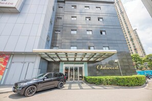 A modern building with a glass entrance, a car parked in front, and a sign that reads "Oakwood." - Oakwood Residences Shanghai (Shanghai)