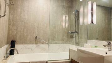 Un baño moderno con ducha envuelta en vidrio, una bañera independiente y un lavabo con tocador.