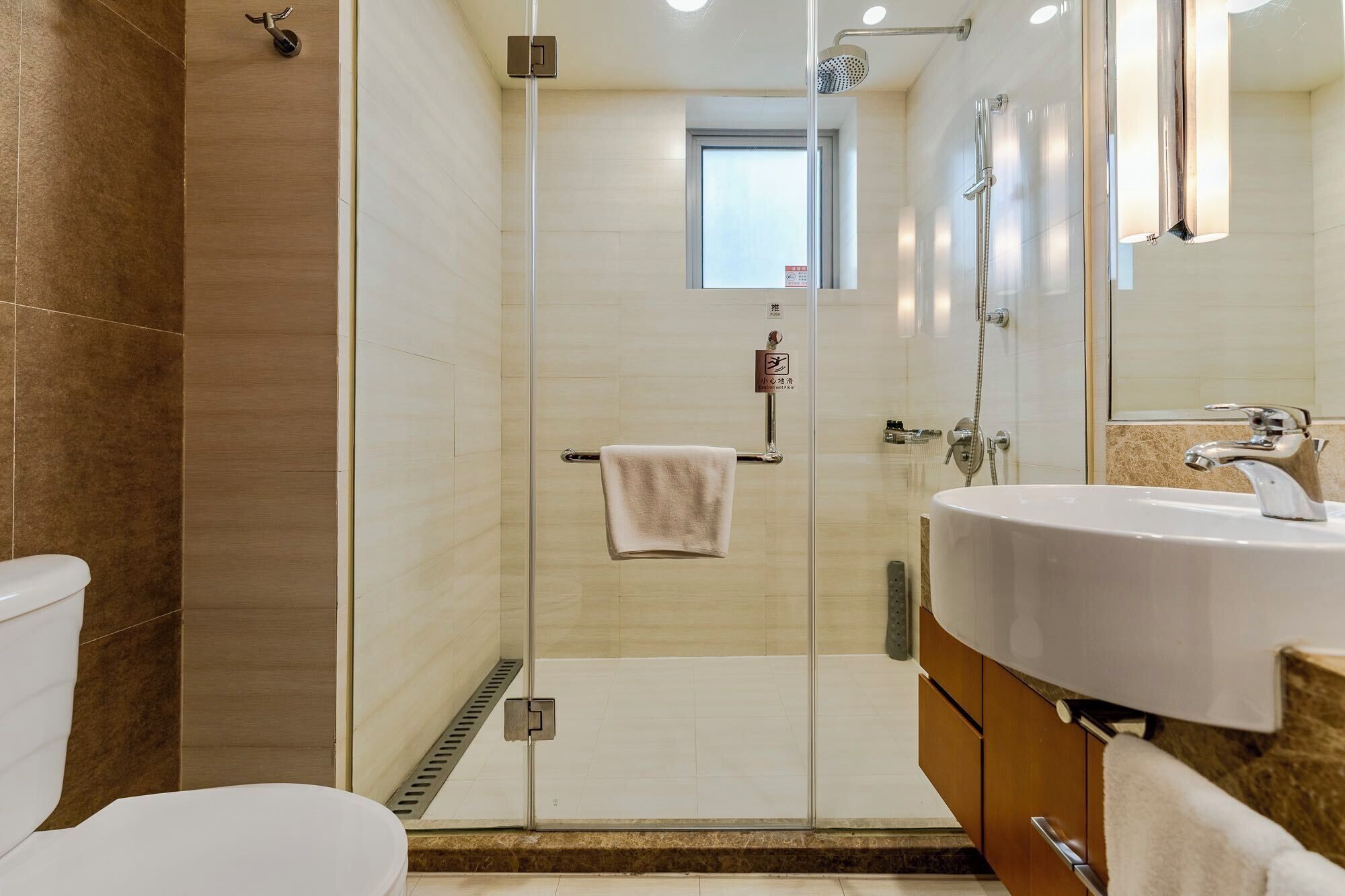 A modern bathroom with a glass shower enclosure, a white sink, and a toilet.