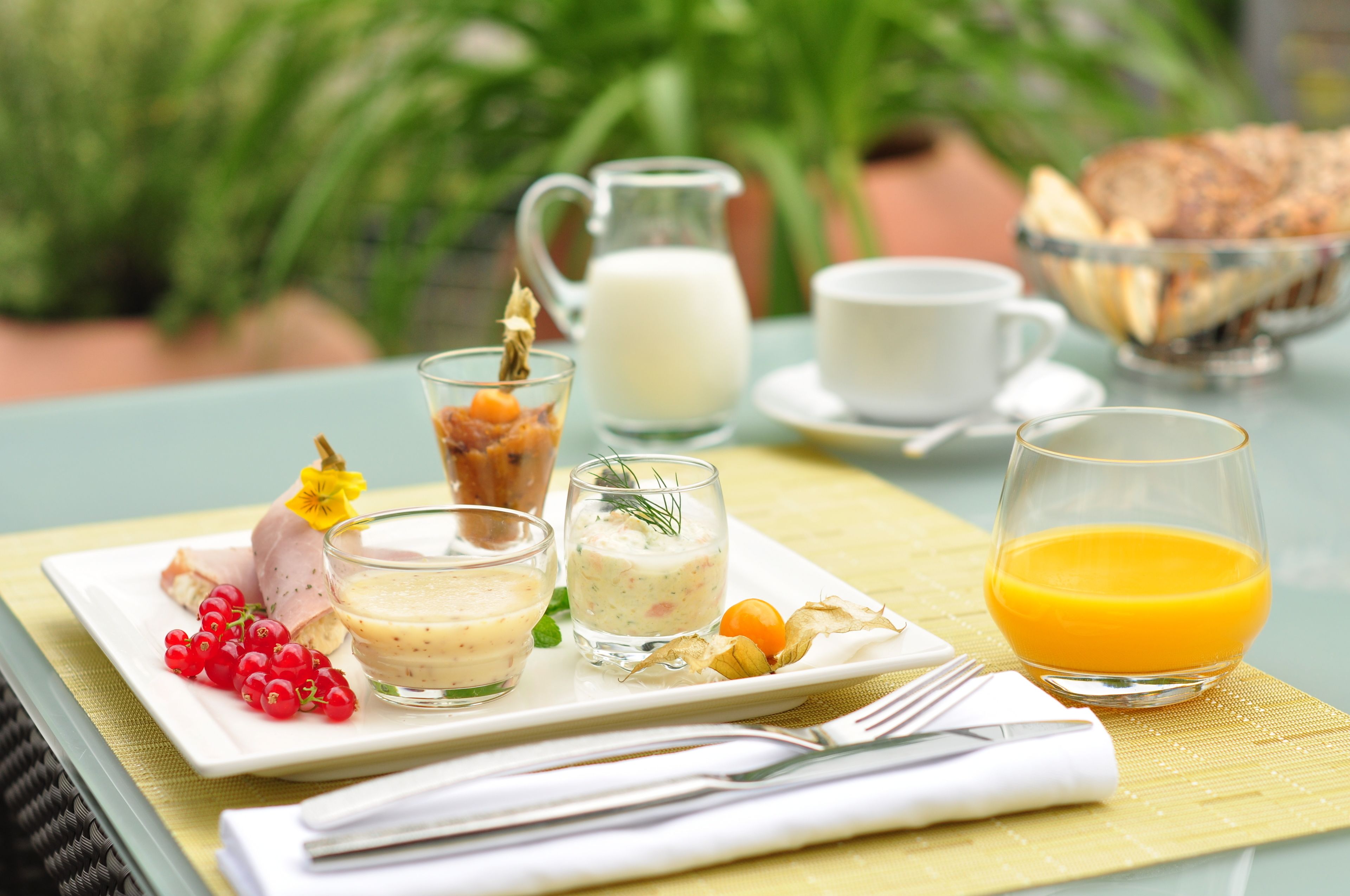 A breakfast setting with a plate of food, a pitcher of milk, a cup of coffee, and a glass of orange juice.