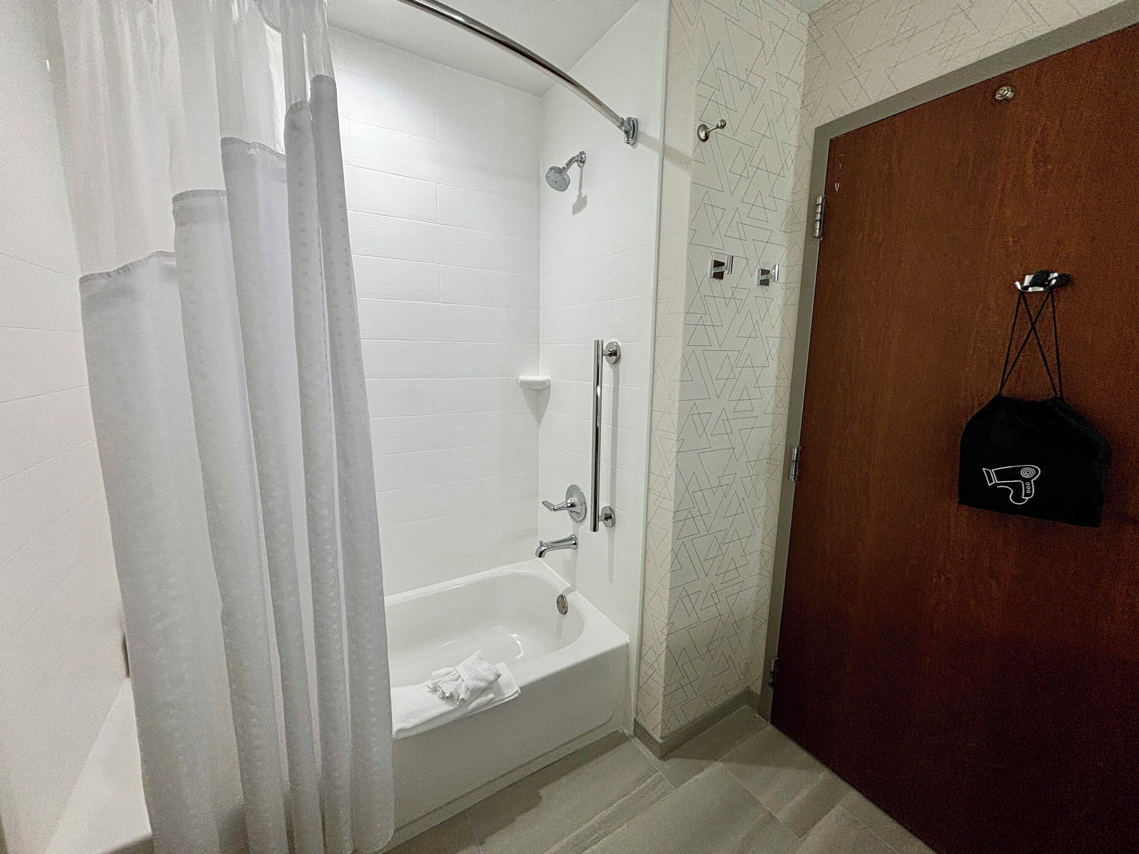 Un baño con ducha, bañera y toalla.