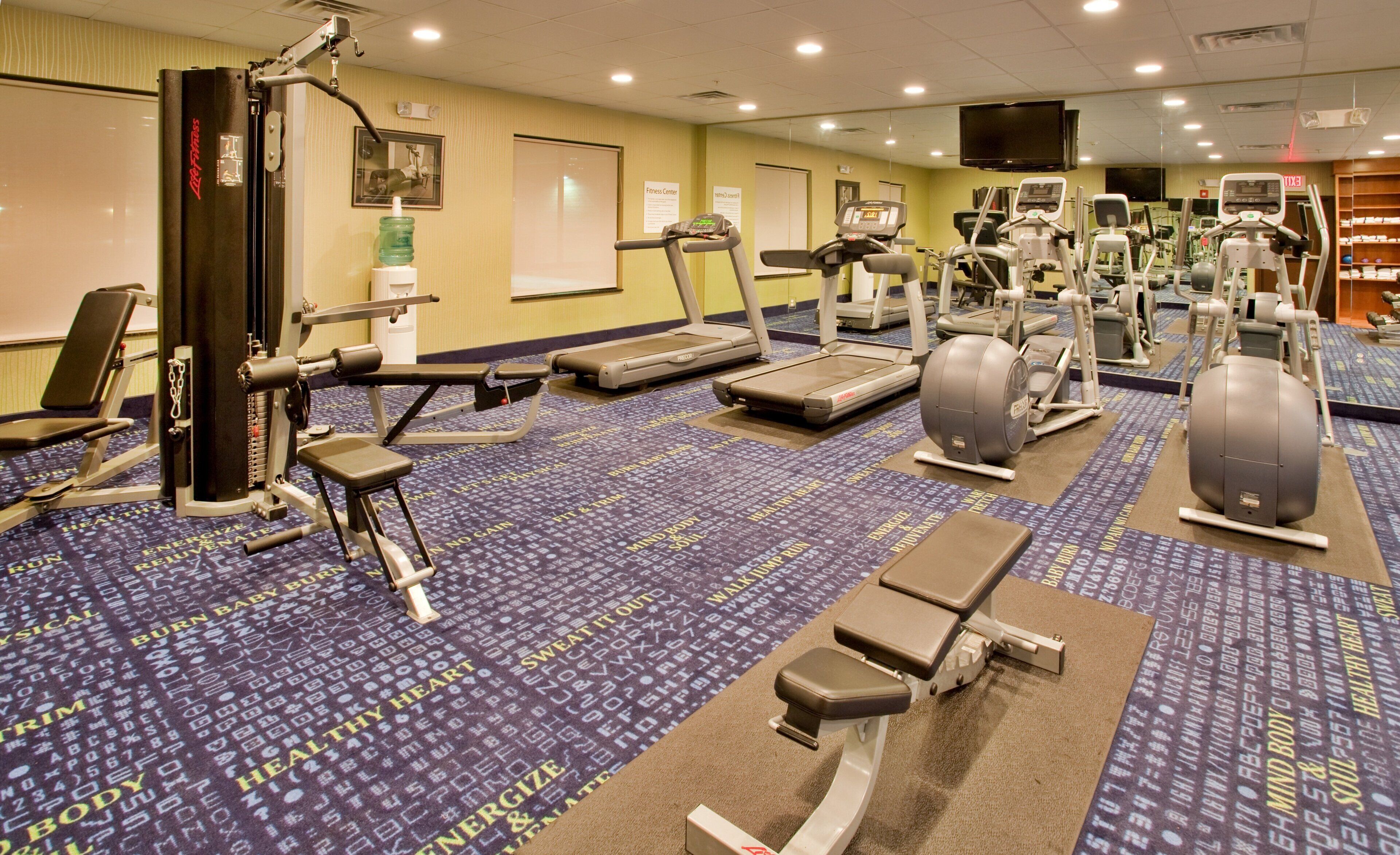 A fitness center with treadmills, elliptical machines, and weight equipment.