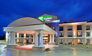 Un hotel Holiday Inn Express con entrada cubierta, varios pisos y fachada bien iluminada.
