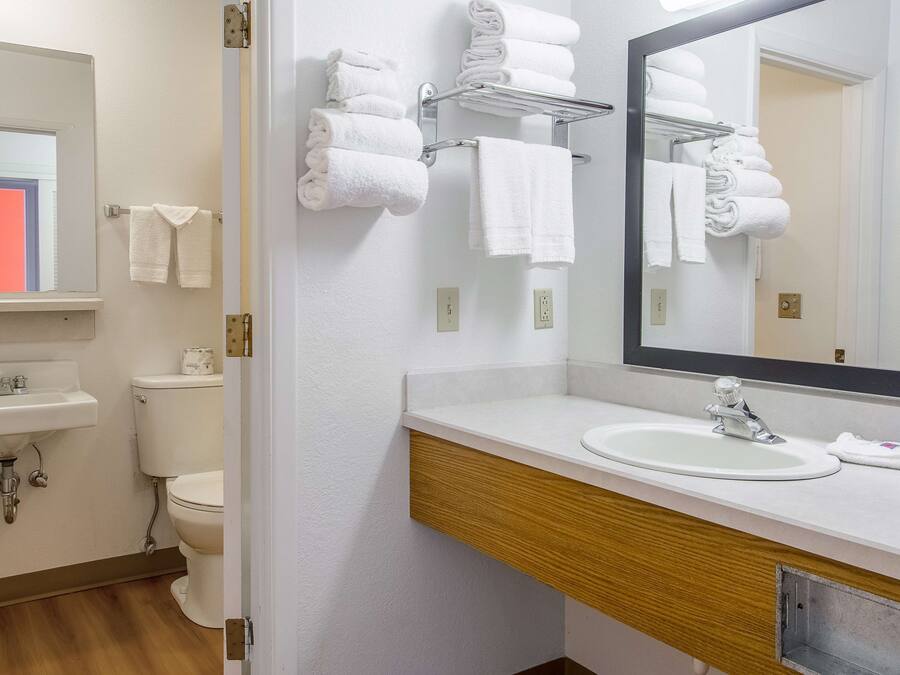 Un baño con lavamanos, espejo, toallero y retrete.