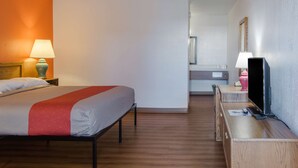A hotel room with a bed, bedside lamp, TV, and a desk with a lamp. - Motel 6 Madras, OR (Madras)