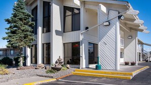 A two-story building with large windows, a visible entrance, and a small outdoor seating area with a planter. - Motel 6 Madras, OR (Madras)