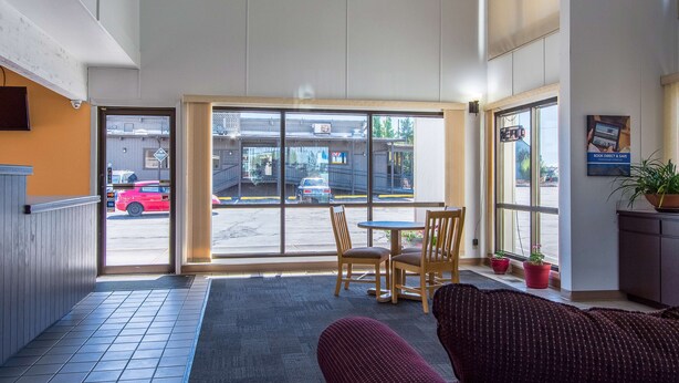 A hotel lobby with a large window, a reception desk, and a seating area with a sofa and chairs. - Motel 6 Madras, OR (Madras)