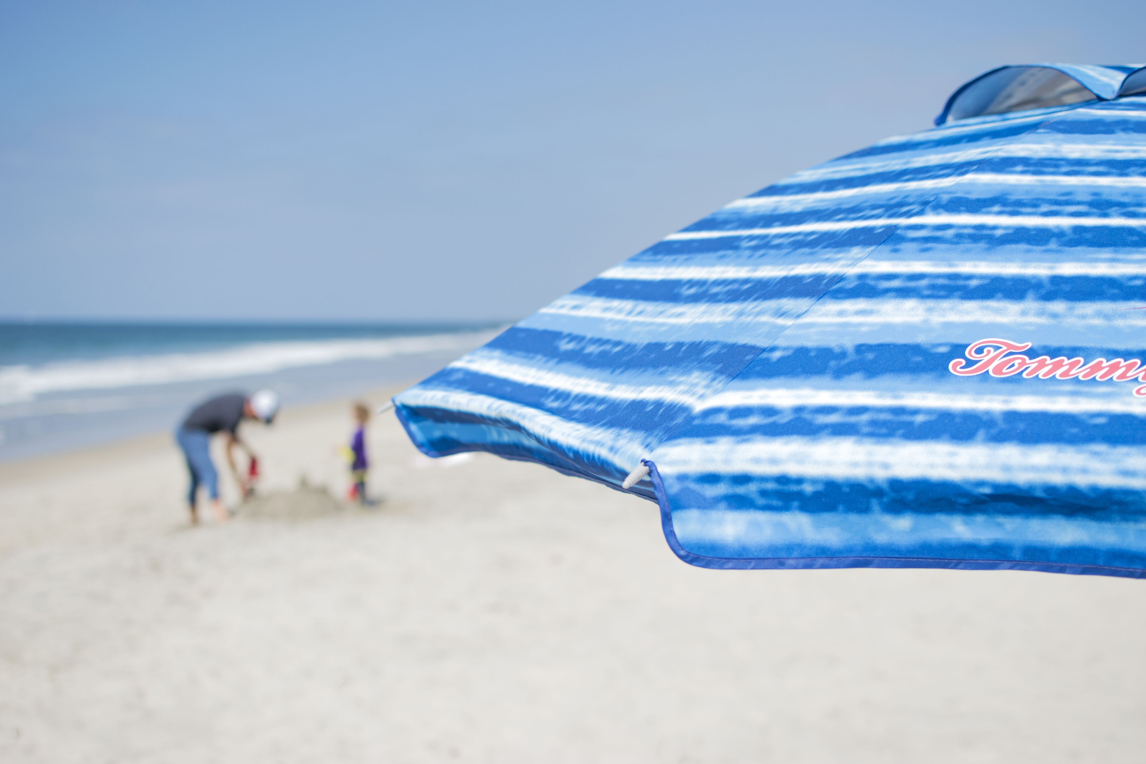 Une scène de plage avec un parasol rayé de bleu et de blanc.