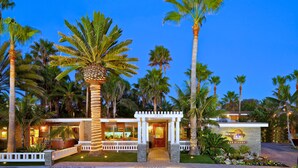 A resort with a well-lit entrance, palm trees, and a stone facade. - Ocean Palms Beach Resort (Carlsbad)