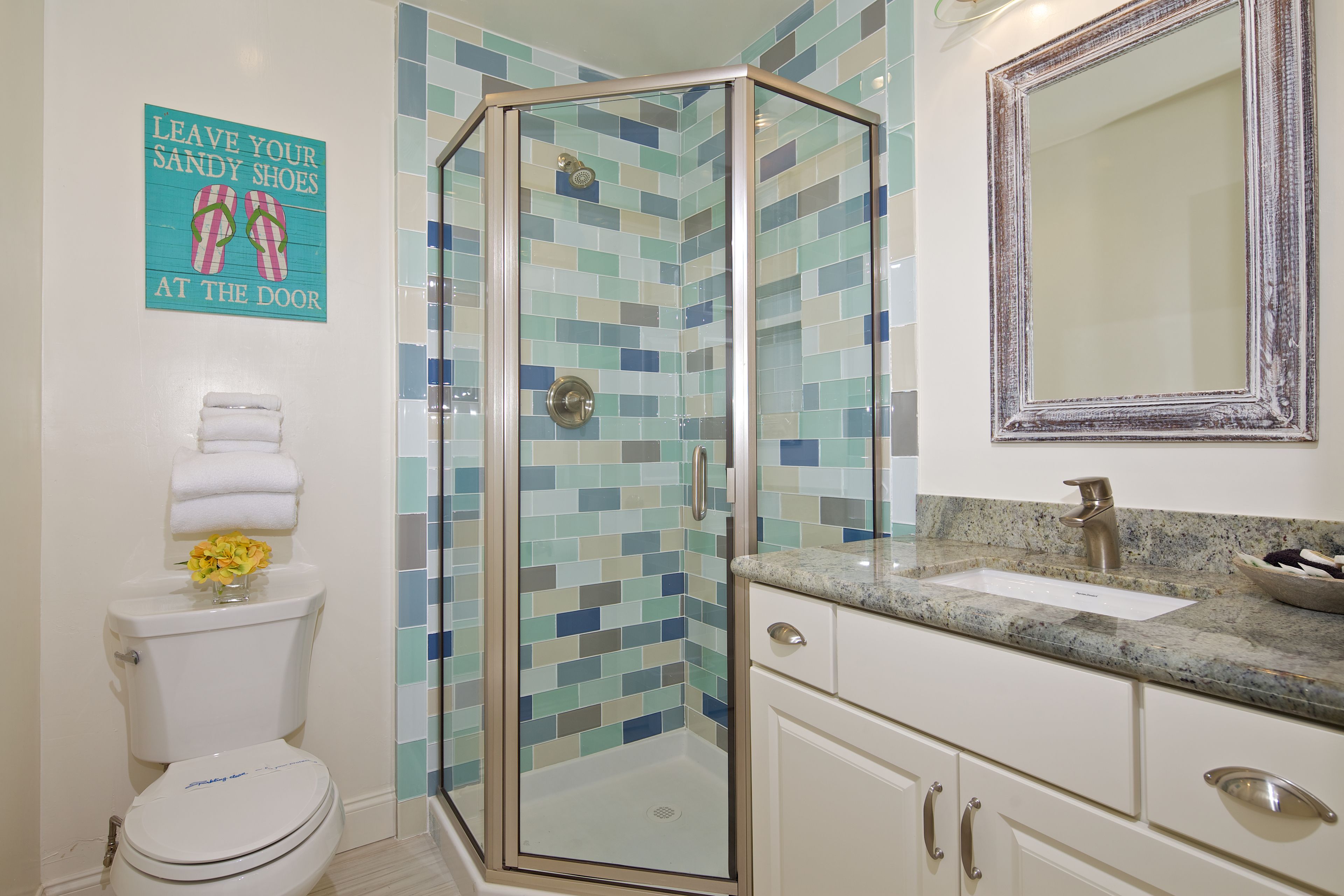 A bathroom with a glass-enclosed shower, a sink, and a toilet.