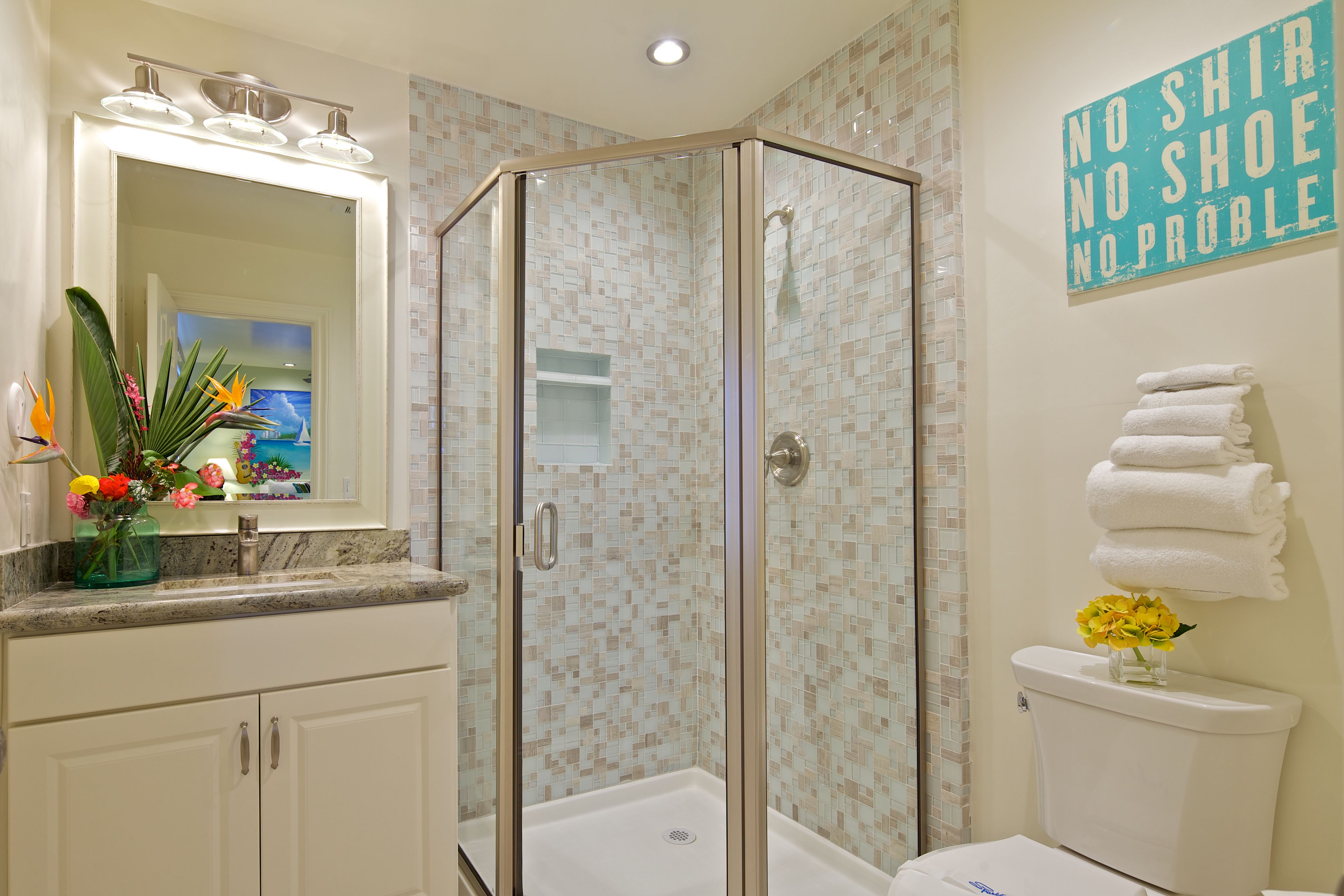 A bathroom with a glass-enclosed shower, a sink with a mirror, and a toilet with a towel rack.