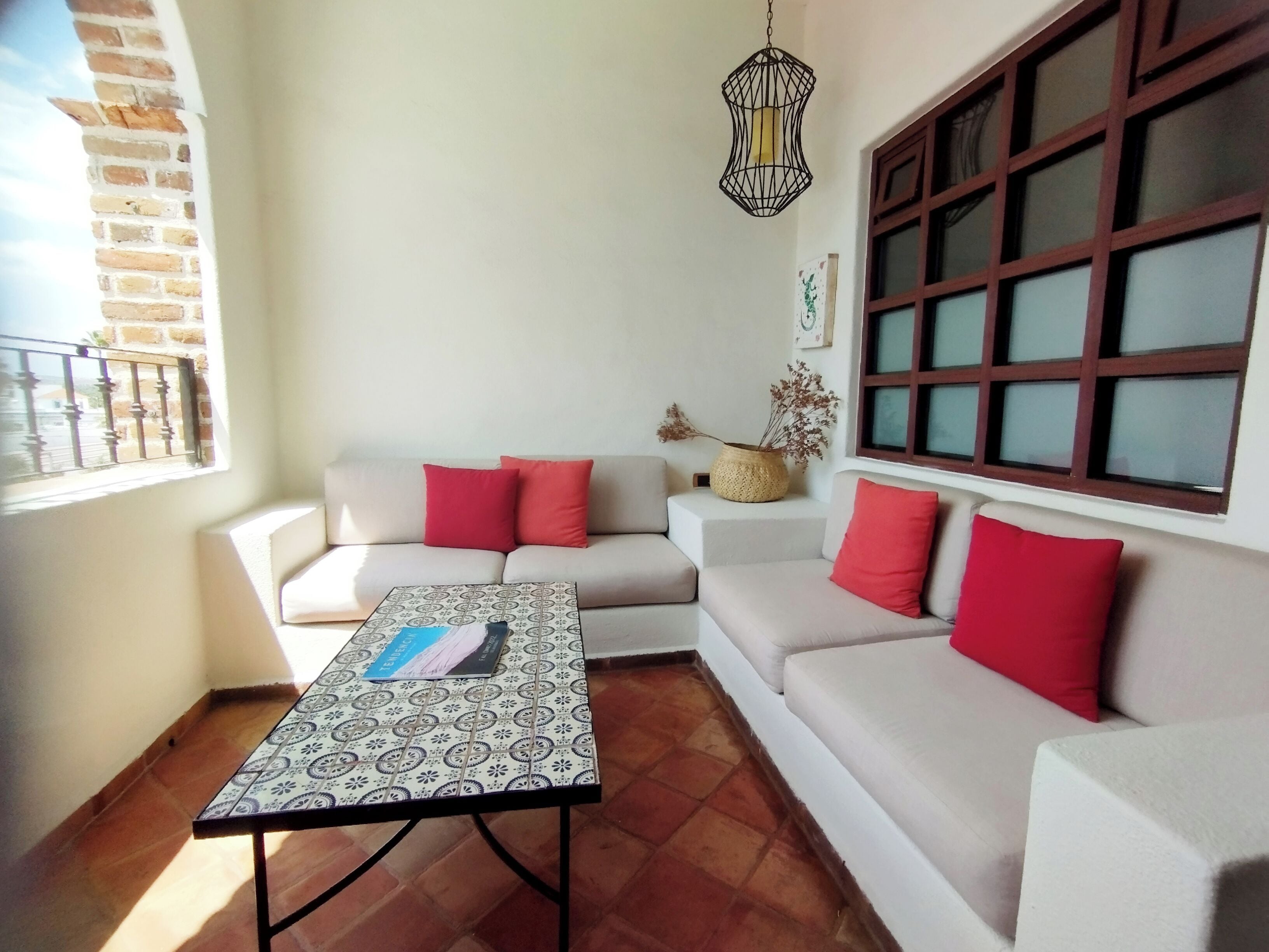 Un salón con un conjunto de sofás, una mesa de centro estampada y una lámpara colgante.