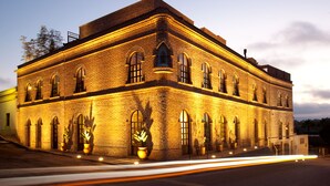 A large, rectangular brick building with multiple arched windows and a flat roof, illuminated by warm lighting.