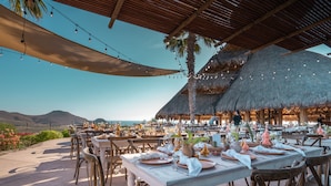 An outdoor dining area with tables set for a meal, overlooking a scenic landscape.