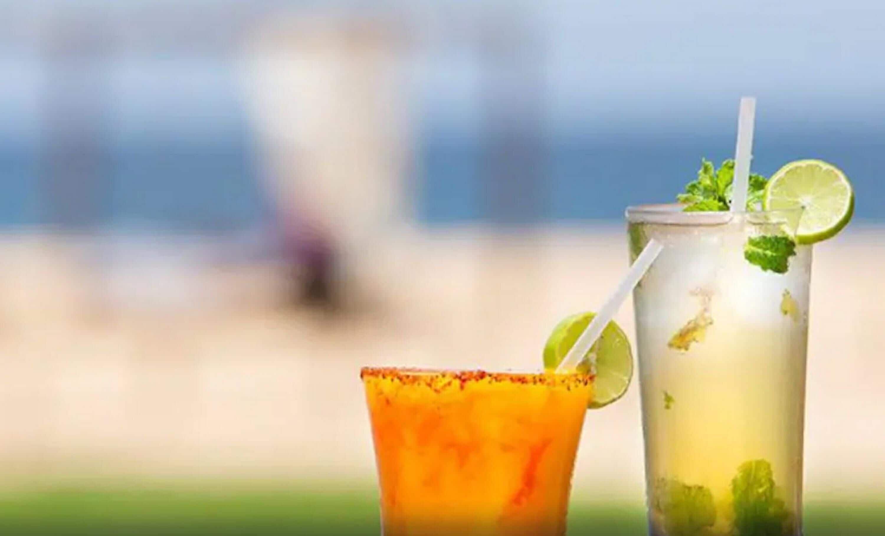 Dos cócteles en una playa, con un fondo desenfocado.