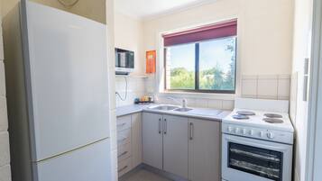 A kitchen with a refrigerator, sink, stove, and cabinets.