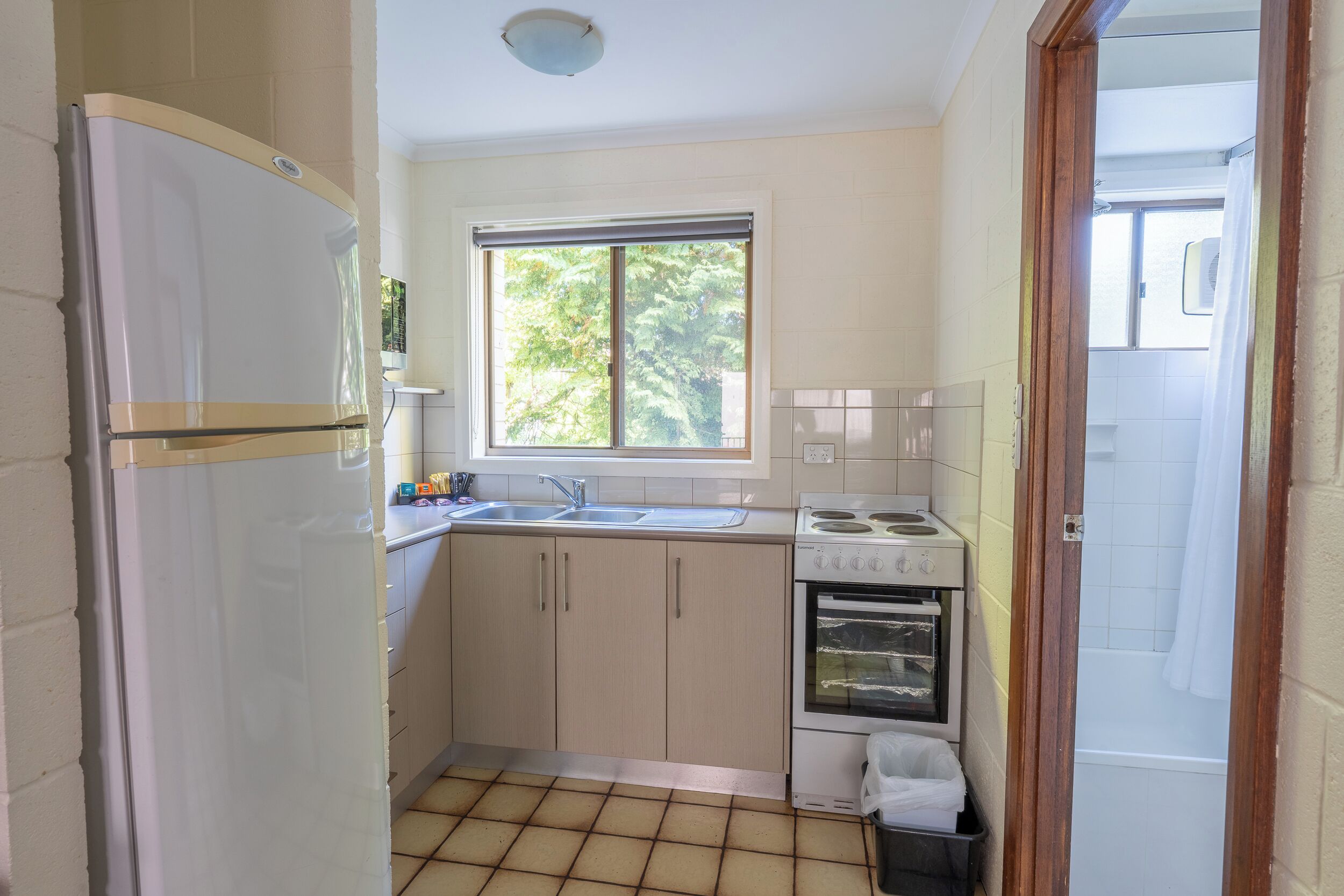 A compact kitchen with a refrigerator, sink, stove, and oven.