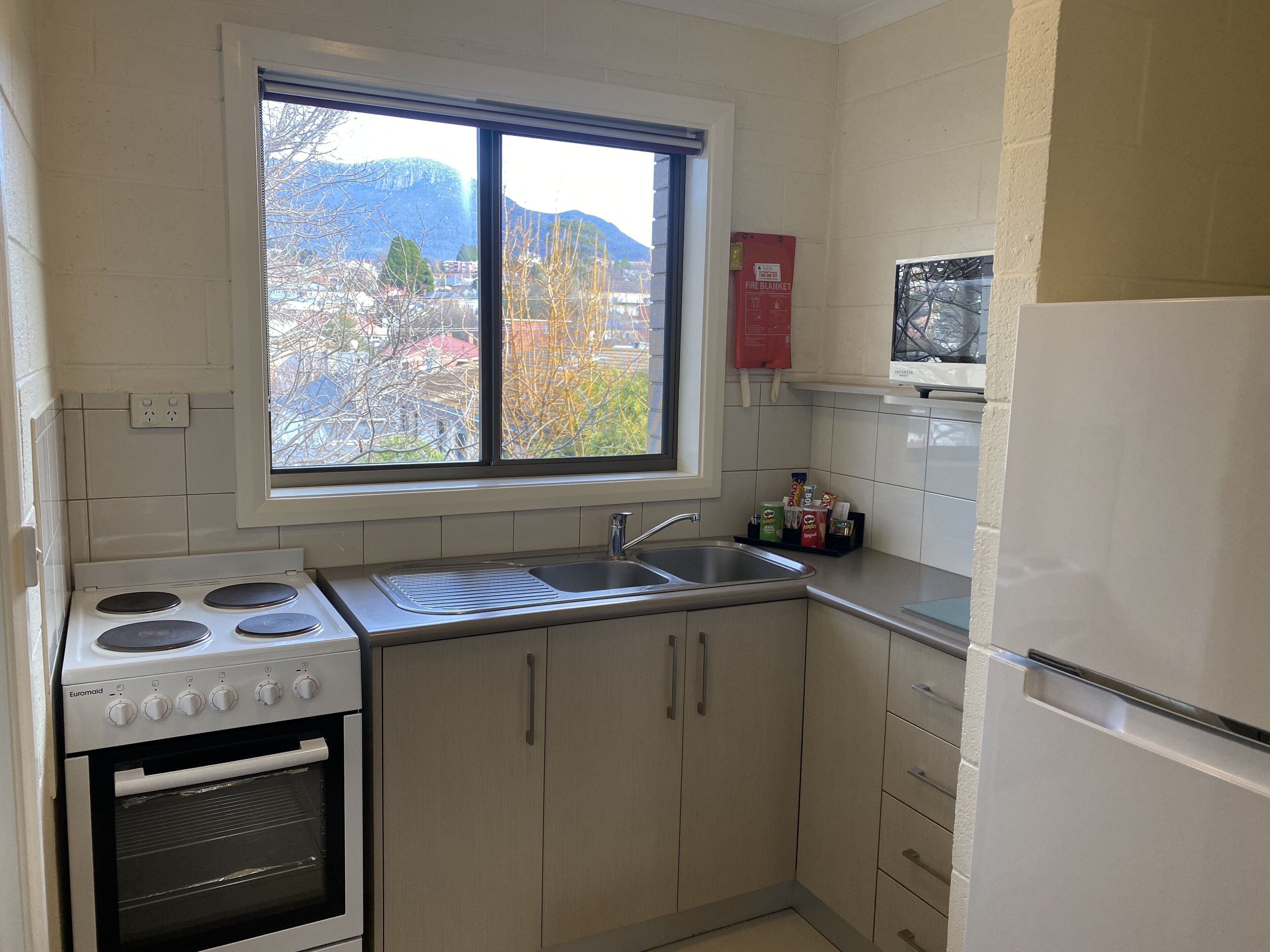 A kitchen with a window, stove, sink, and cabinets.