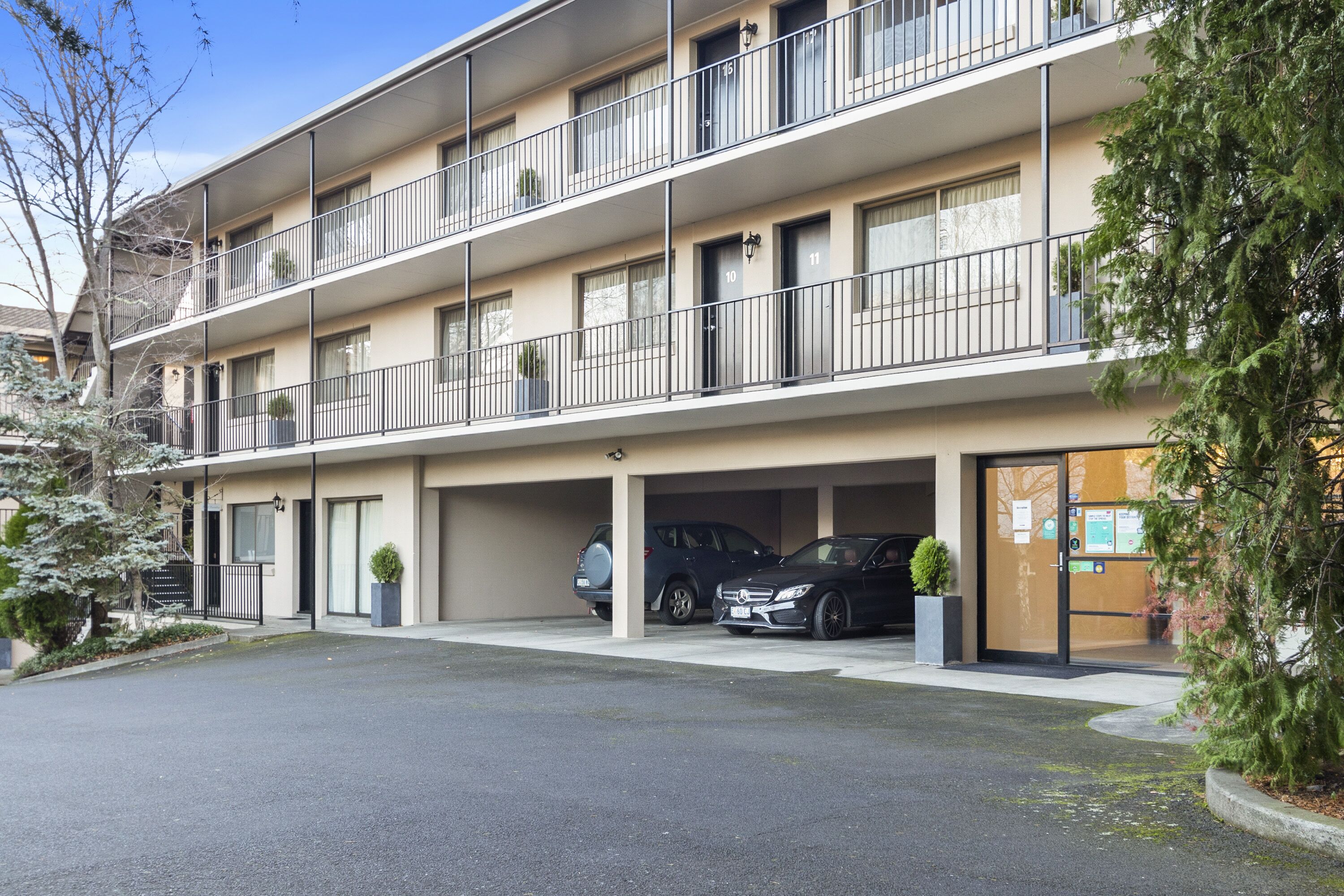 A multi-story residential building with balconies, a parking garage, and a driveway.