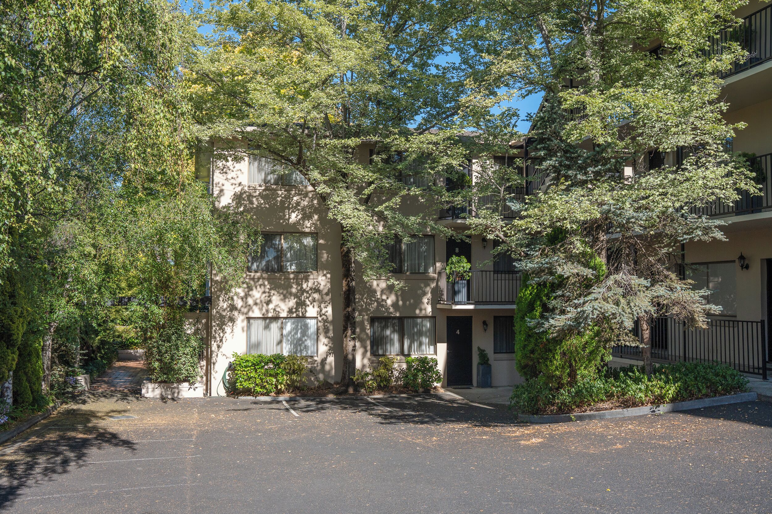 A multi-story residential building with a central courtyard, surrounded by trees and greenery.