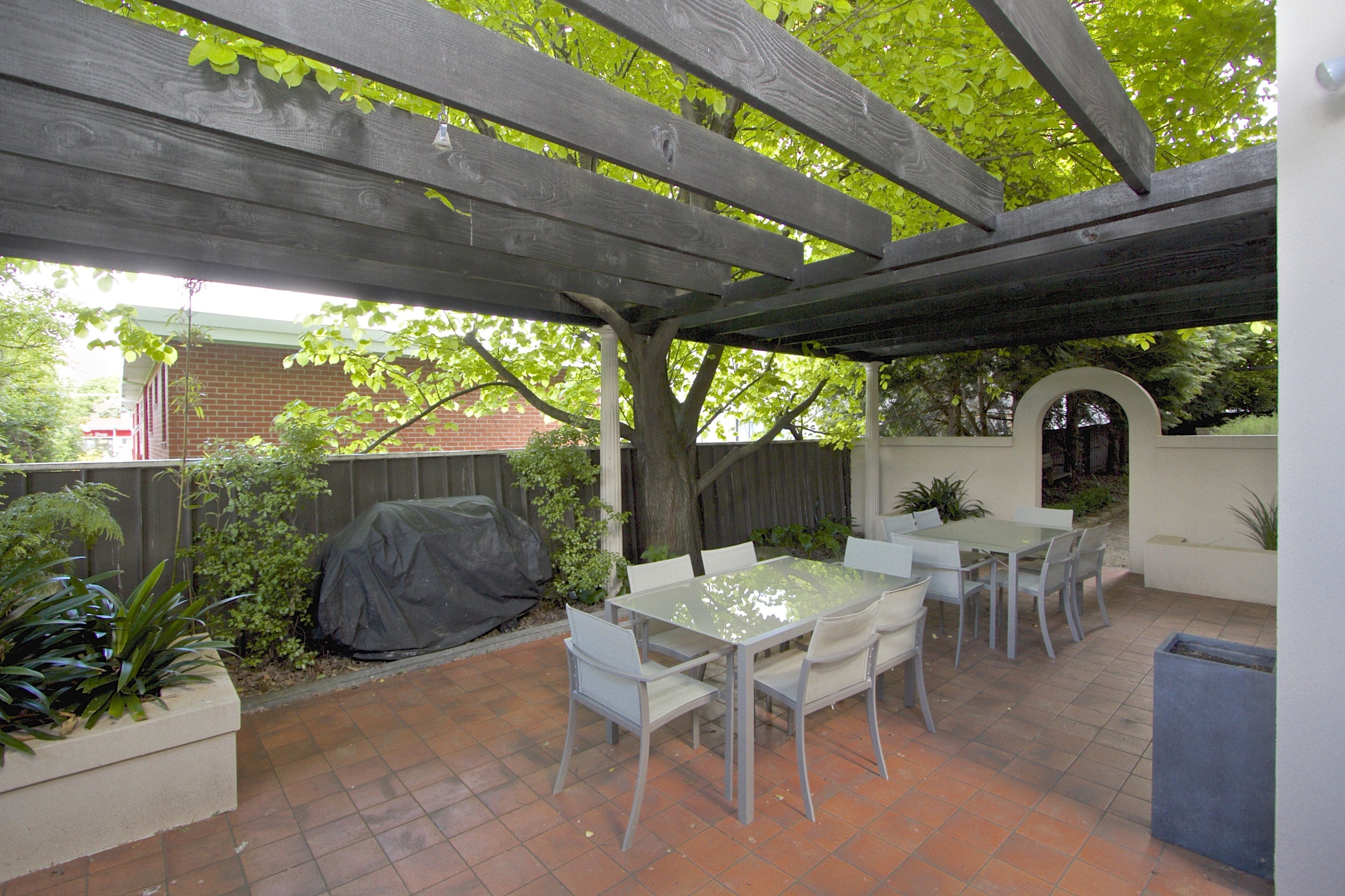 Un patio exterior con un área de estar techada, una mesa y sillas.