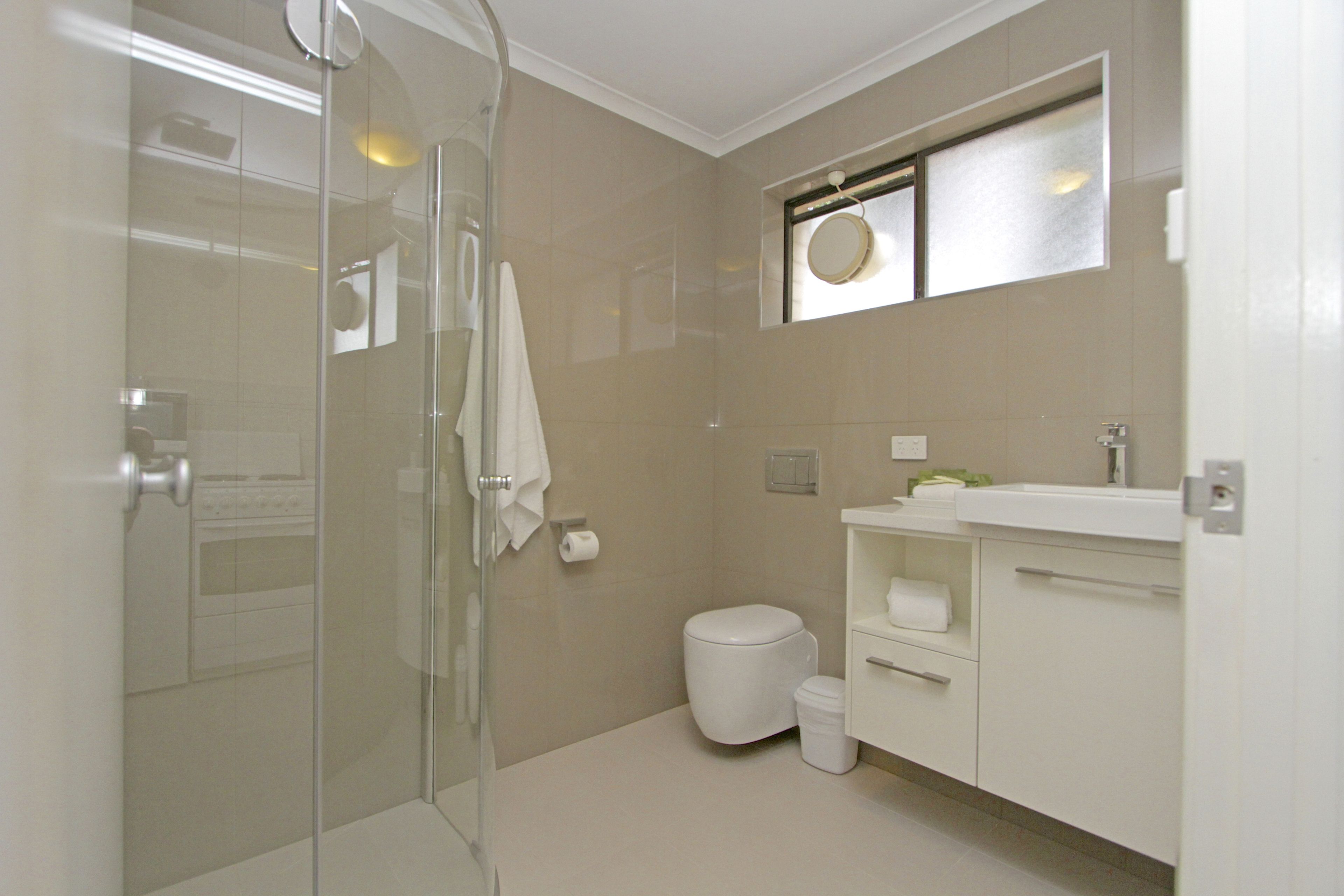 Un bagno moderno con box doccia in vetro, un water e un mobile lavabo con lavandino e specchio.