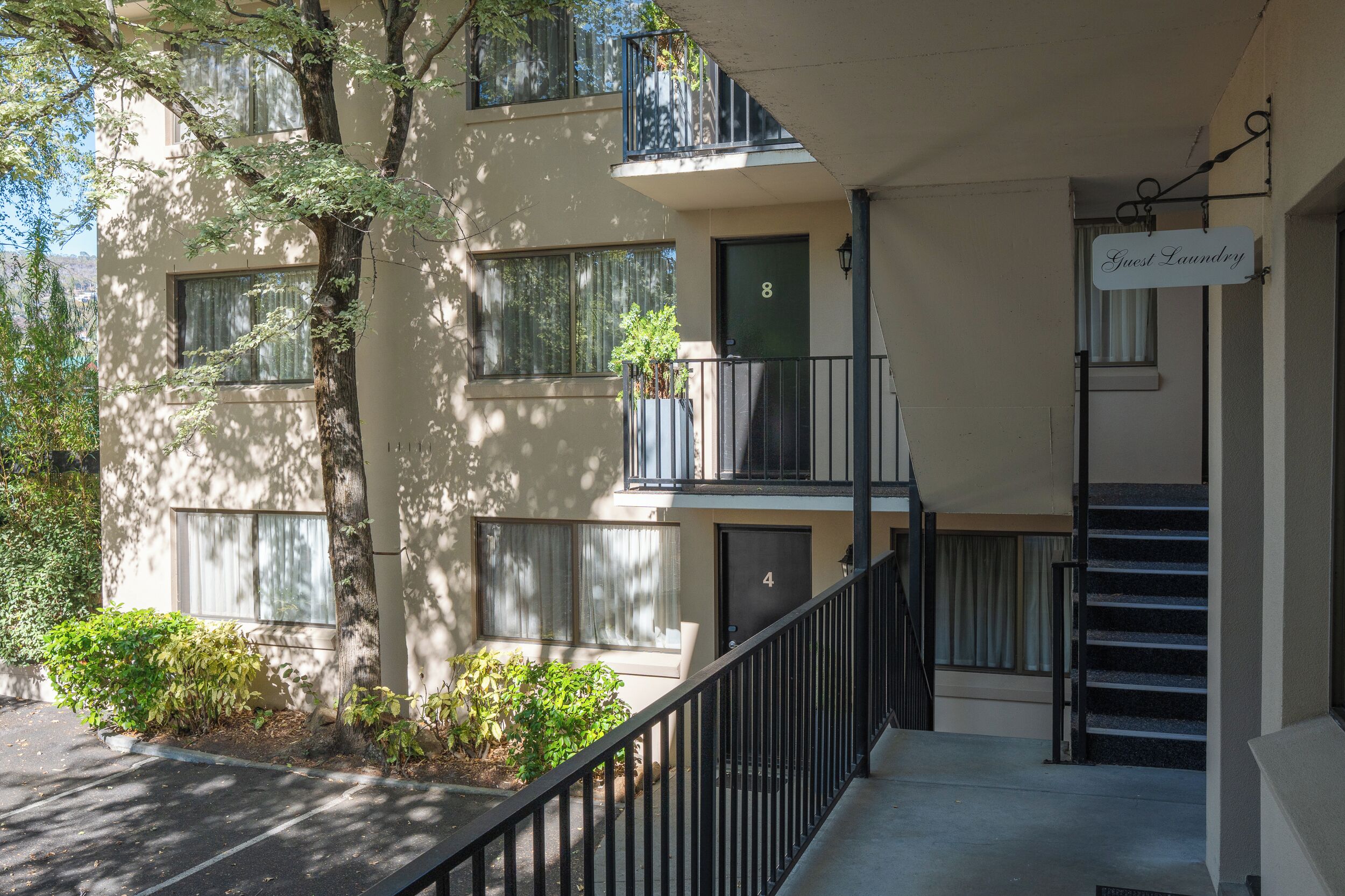 A two-story building with a balcony, a sign indicating guest laundry, and a staircase leading to the entrance.