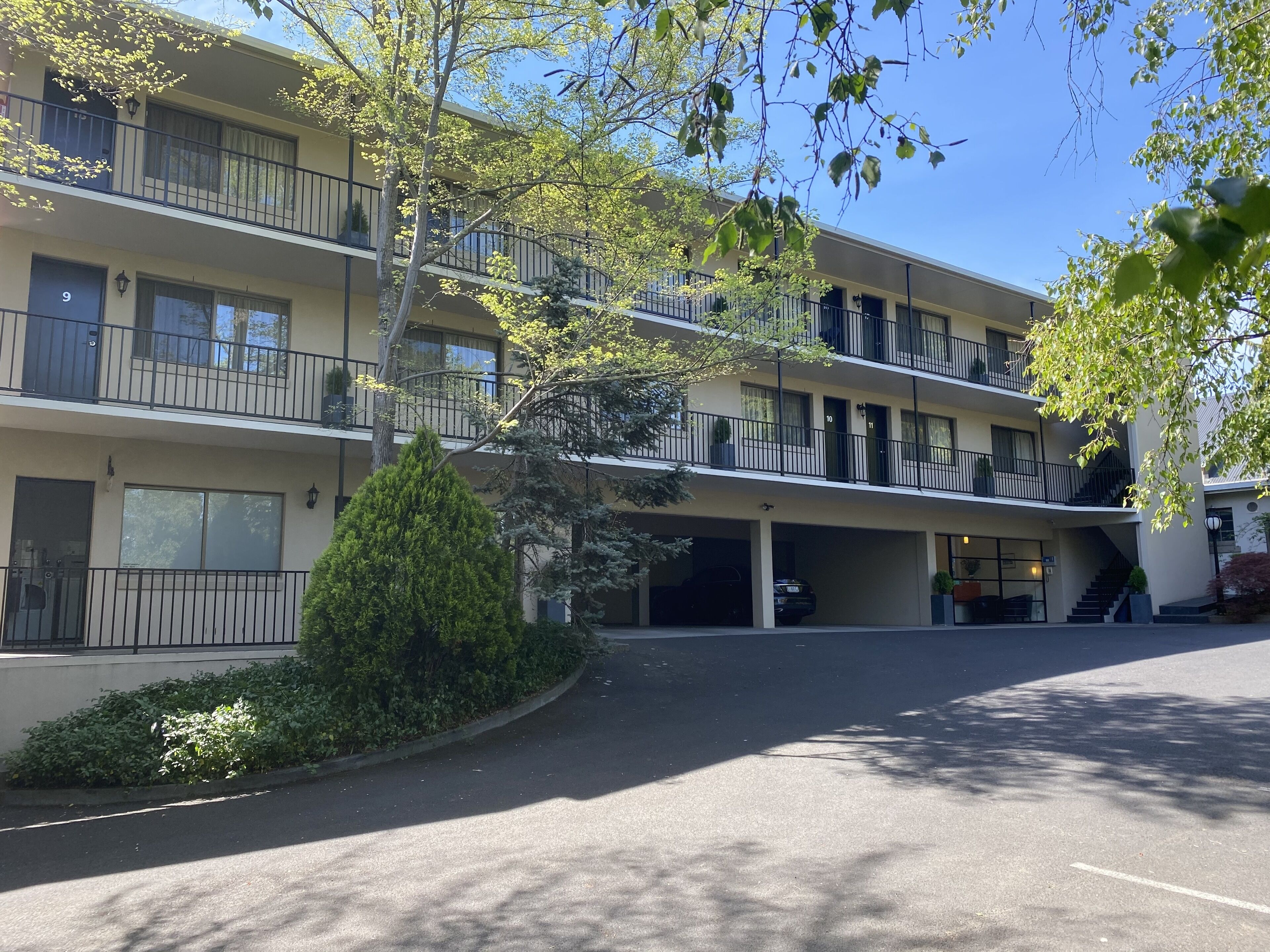 A multi-story motel with balconies, a parking garage, and a clear sky.