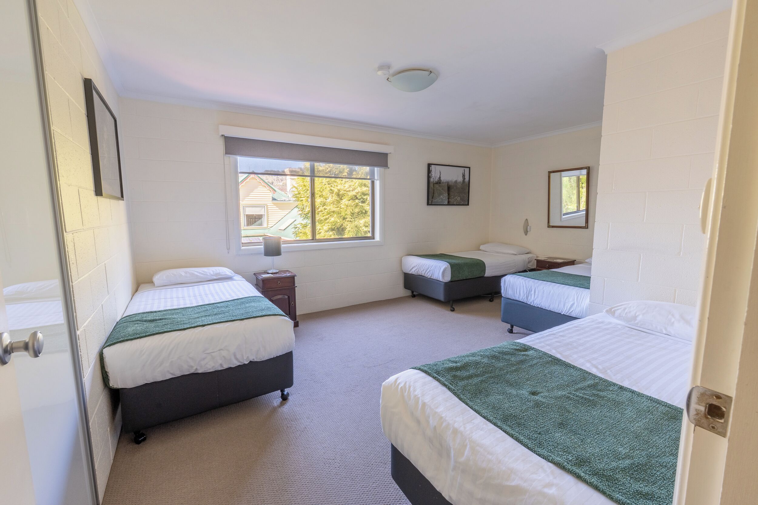 A room with two beds, a window, and a door.